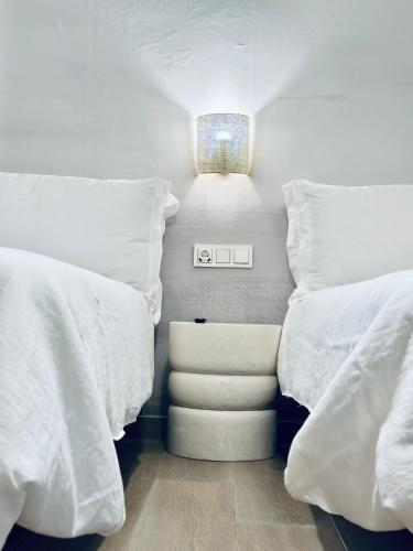 two beds with white pillows and a light in a room at Apartamentos Noja Playa in Noja