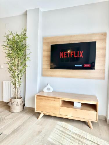 a living room with a television on a wall at Apartamentos Noja Playa in Noja