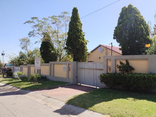 uma cerca em frente a uma casa com árvores em Tokelo Guesthouse Emalahleni em Witbank