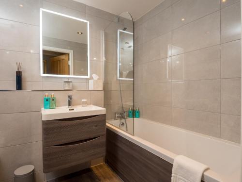 a bathroom with a sink and a tub and a mirror at Durham Riverside Apartments in Durham