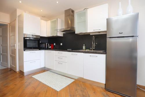 une cuisine avec des armoires blanches et un réfrigérateur en acier inoxydable dans l'établissement IMMOGROOM - Beautiful and Cosy - Air conditioner - 5 min from beaches, à Cannes