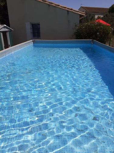 une grande piscine bleue à côté d'une maison dans l'établissement tiny house indépendante climatisée, à Moulès