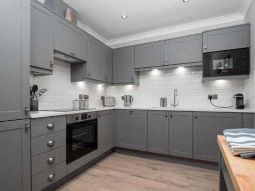 a kitchen with gray cabinets and white appliances at Durham Riverside Apartments in Durham