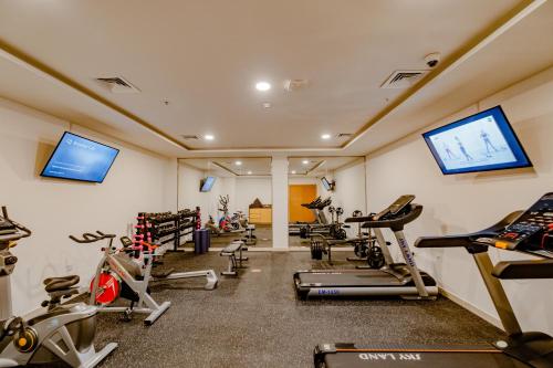 a gym with several tread machines and a flat screen tv at Peony Hotel in Dubai