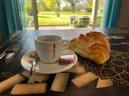 CAMPING DE LA CHALARONNE في Saint-Didier-sur-Chalaronne: كوب من القهوة وكرواسون على طاولة