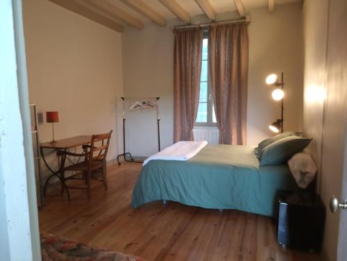 Schlafzimmer mit einem Bett, einem Tisch und einem Fenster in der Unterkunft Lulu in Castelmoron-sur-Lot