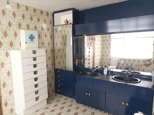 uma casa de banho com armários azuis e 2 lavatórios e uma janela em Lalmendra. 