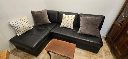 a black leather couch with pillows and a table at Bel & ancien appartement T3 rénové dans Sartène in Sartène