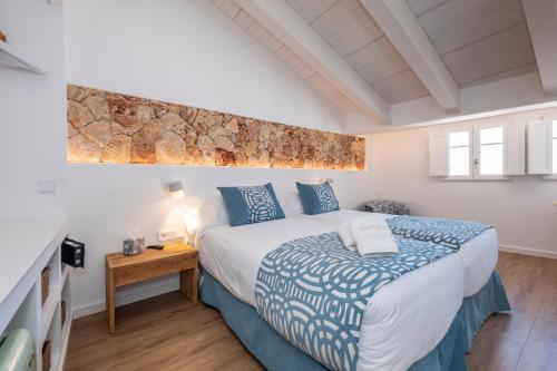 a bedroom with a large bed with blue pillows at Hotel S'Antiga Adults Only in Es Mercadal