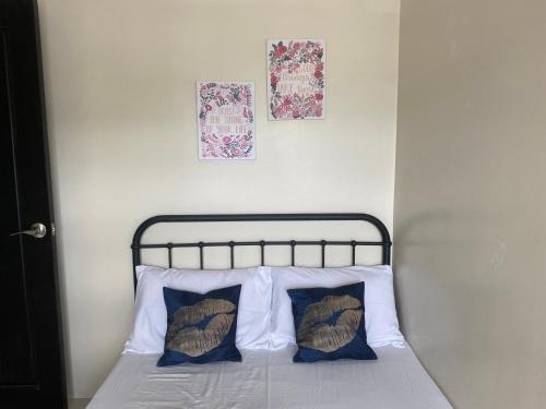a bed with two pillows and two pictures on the wall at Cebu One Pavillion Place by P&J in Cebu City