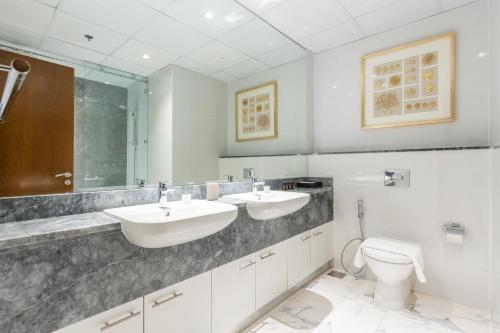 a bathroom with two sinks and a toilet at Lux BnB I Amna Tower I Panaromic Views in Dubai