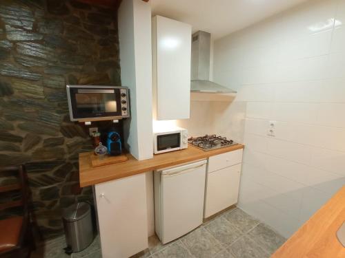 a kitchen with a counter with a microwave and a tv at Casa Rústica da Lavandeira in Valongo dos Azeites