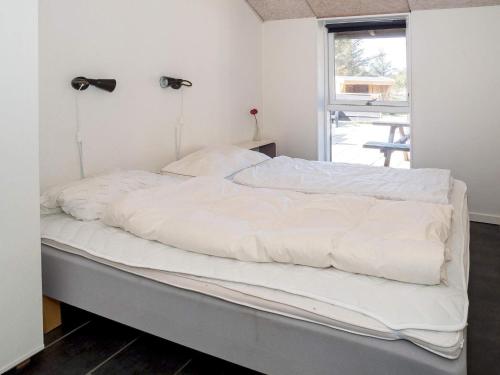 - une chambre avec un lit doté de draps blancs et une fenêtre dans l'établissement Holiday home Snedsted V, à Snedsted