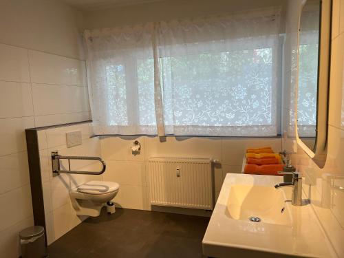 a bathroom with a sink and a toilet and a window at Ferienwohnungen Meeres-Brise - Weißer Weg in Bad Zwischenahn