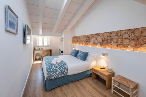 a bedroom with a king sized bed and a stone wall at Hotel S'Antiga Adults Only in Es Mercadal