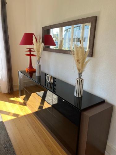 een woonkamer met een glazen tafel met 2 lampen en een spiegel bij Appartement de Prestige au centre avec jardin privé in Colmar