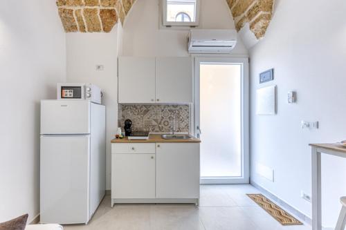 a kitchen with white cabinets and a refrigerator at Bilocale con vasca idromassaggio in Presicce