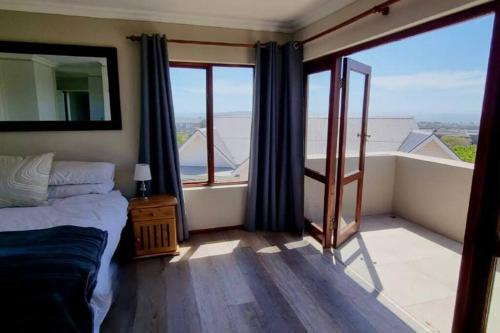 a bedroom with a bed and a balcony with a mirror at Zoete Inval - 3 Bedroom Self Catering Home. in Langebaan