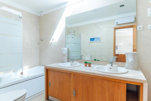 a bathroom with two sinks and a tub and a mirror at Villa Aroeira II in Aroeira