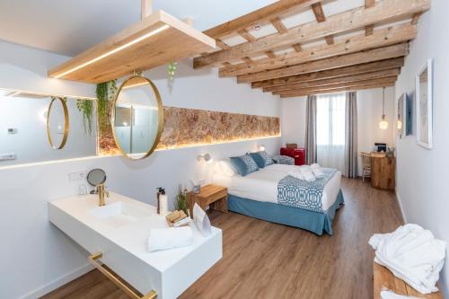 a bedroom with a bed and a sink and a mirror at Hotel S'Antiga Adults Only in Es Mercadal