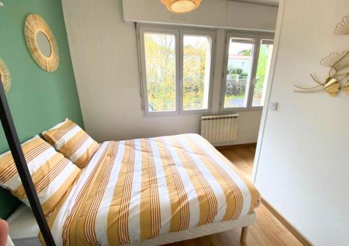 ein Schlafzimmer mit einem Bett in einem Zimmer mit Fenstern in der Unterkunft Au 45' - Poitiers - Futuroscope - La Conciergerie in Poitiers