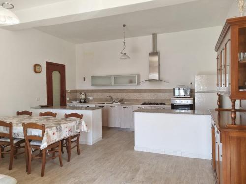 una cocina con mesa y sillas y una cocina con paredes blancas. en Bella D'Estate - 10 minutes from the beach en Isquia