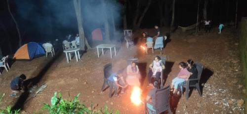 a group of people sitting around a fire at night at Hotel Hilltone- panorama bungalow matheran in Matheran