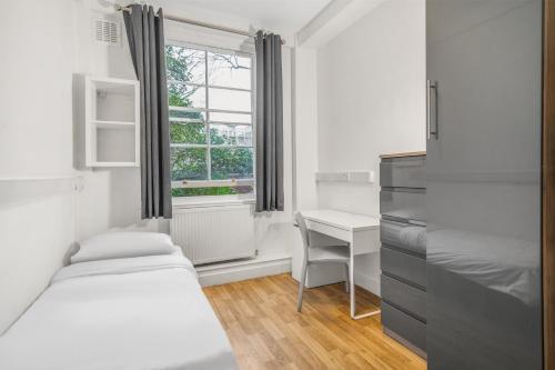 1 Schlafzimmer mit 2 Betten, einem Schreibtisch und einem Fenster in der Unterkunft Bowden Court (Notting Hill) in London