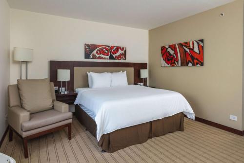 a bedroom with a large bed and a chair at Wyndham Garden San Jose Escazu, Costa Rica in San José