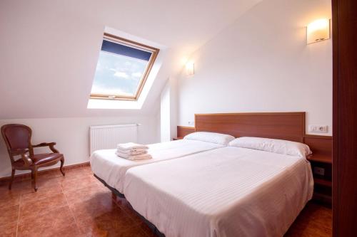1 dormitorio con 1 cama grande y 1 silla en Hotel Darío, en Lugo