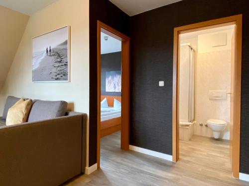 a living room with a couch and a bathroom at Friesenhof Hotel-Restaurant-Reitanlage in Trassenheide