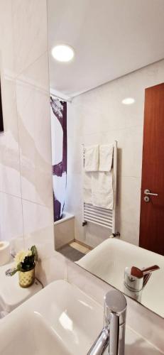 a white bathroom with a sink and a mirror at Charming Pedra in Braga