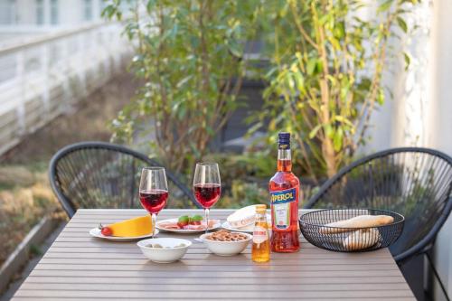 a wooden table with two glasses of wine and food at Brera Serviced Apartments Munich Schwabing in Munich