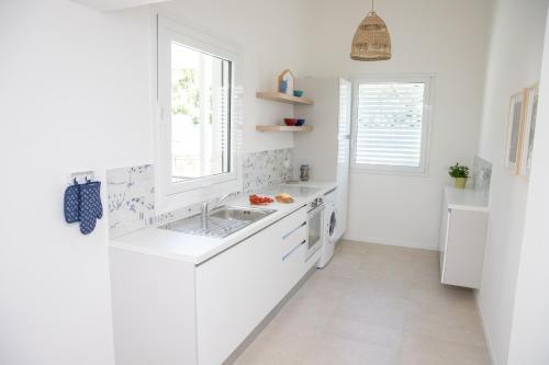 una cucina bianca con lavandino e finestra di Villa Ravanica a Marina di Ragusa