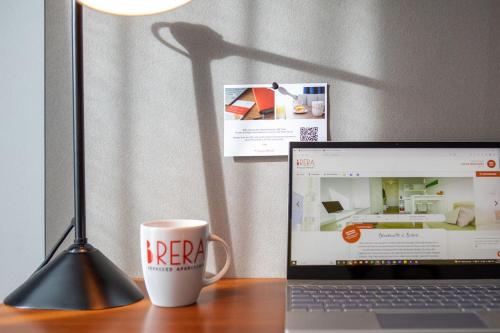 a coffee cup sitting next to a laptop on a desk at Brera Serviced Apartments Munich Schwabing in Munich
