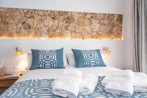 a bedroom with a bed with blue and white pillows at Hotel S'Antiga Adults Only in Es Mercadal