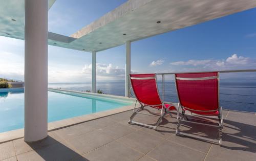 two red chairs sitting next to a swimming pool at Super Luxurious Villa - 600m² - Up to 22 people in Edipsos