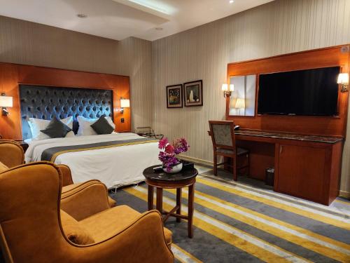 a hotel room with a bed and a flat screen tv at Shaty Alhayat Hotel Suites in Jeddah
