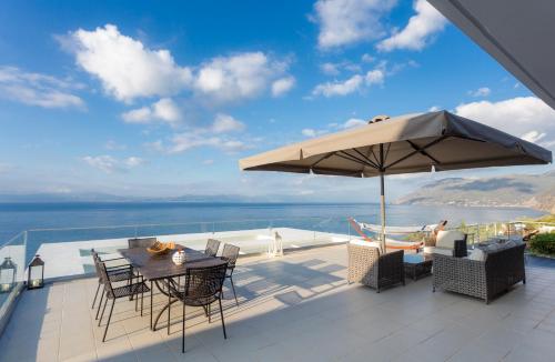 a patio with an umbrella and a table and chairs at Super Luxurious Villa - 600m² - Up to 22 people in Edipsos