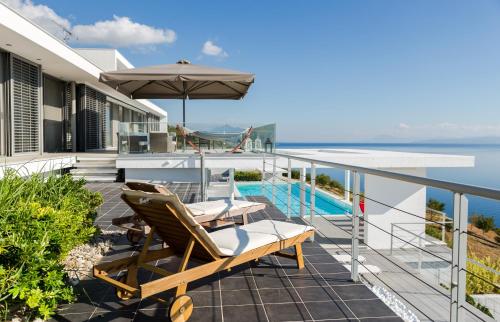 a balcony with chairs and an umbrella and a pool at Super Luxurious Villa - 600m² - Up to 22 people in Edipsos