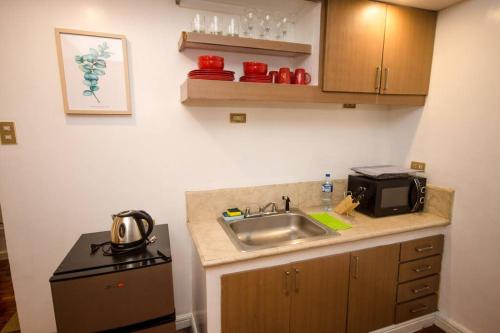 a small kitchen with a sink and a microwave at Poblacion Studio Makati Pili Suite 1BR 47sqm in Manila