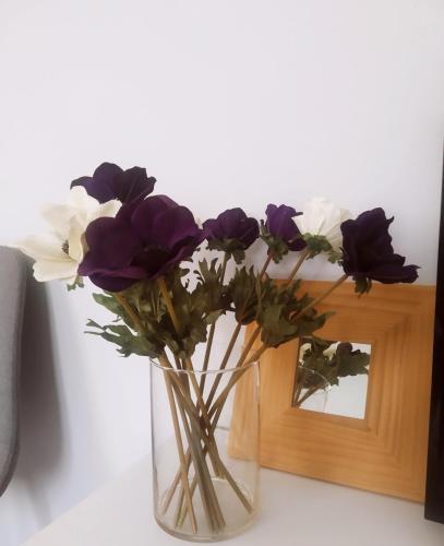 a vase filled with purple and white flowers on a table at Xrysa's Central City Apartment in Mesolongion