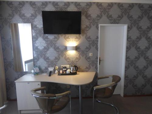 a room with a table with two chairs and a television on the wall at Landhaus "Am Sonnenberg" in Diekholzen