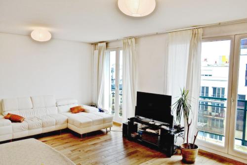 a living room with a white couch and a tv at Stunning loft - sunny terrace - Paris in Paris