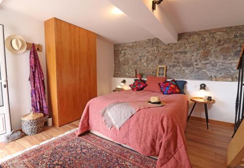 a bedroom with a bed and a stone wall at Casa das Rosas by Homing in Arco da Calheta