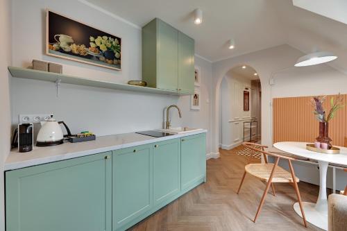a kitchen with blue cabinets and a table in a room at Downtown Apartments The Love Bridge - Na Piaskach in Gdańsk