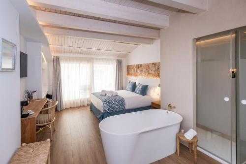 a bathroom with a tub and a bed in a room at Hotel S'Antiga Adults Only in Es Mercadal