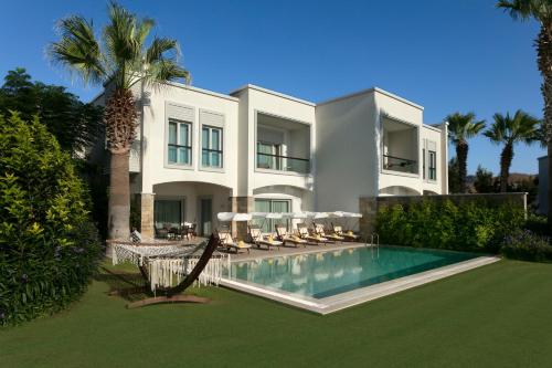 a large white house with a swimming pool and palm trees at Xanadu Island in Akyarlar