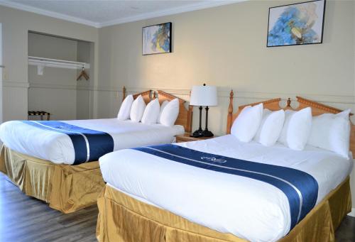 Habitación de hotel con 2 camas con sábanas blancas y azules en Omeo Suites Glass Beach, en Fort Bragg