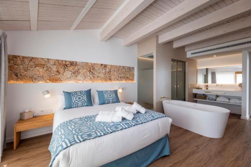 a bedroom with a large bed and a bath tub at Hotel S'Antiga Adults Only in Es Mercadal